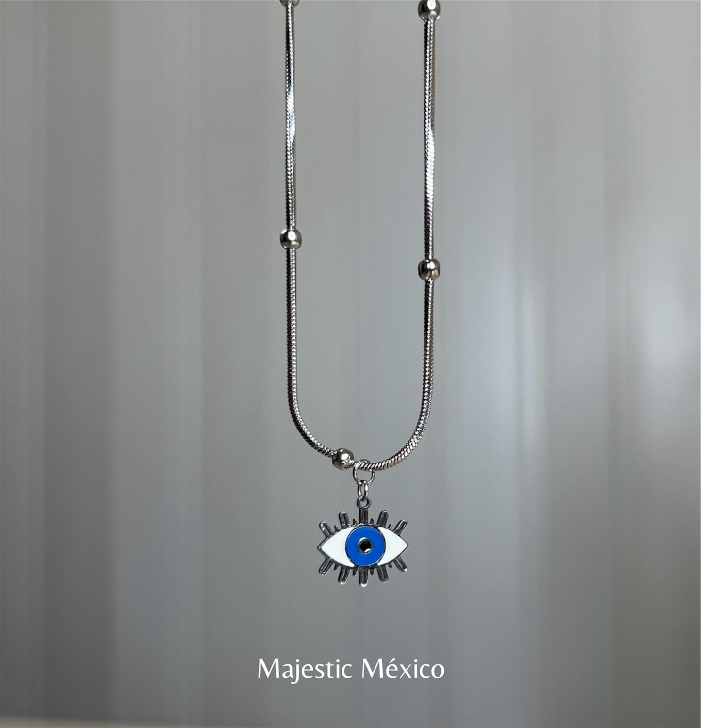 Collar de acero inoxidable plateado con cadena de balines y dije de ojito azul con pestañas, joyería minimalista Majestic México