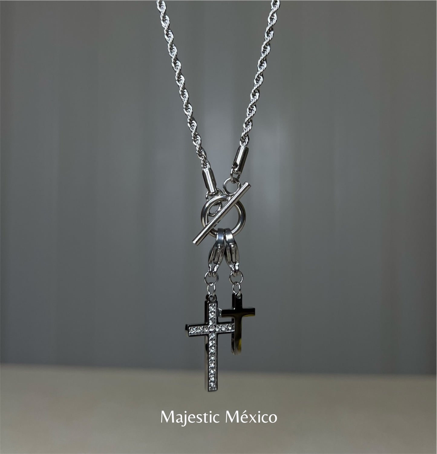 Collar de acero inoxidable plateado con dos cruces, una con cristales y broche tipo T, joyería espiritual Majestic México